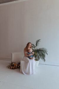 Mother cuddling newborn in modern photography studio with floral props