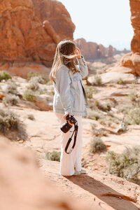 Photographer looking out at the red rocks during midday in Arches National Park 
