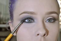 makeup brush with two different eye makeup looks on model