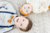 Baby and toddler laying on a blanket looking up