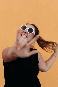 Lyndi Benson, Body Love Coach of the LIVE BIG Collective posing confidently with sunglasses on 