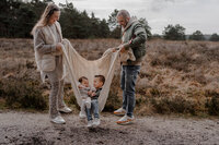 ouders schommelen kinderen in dekentje