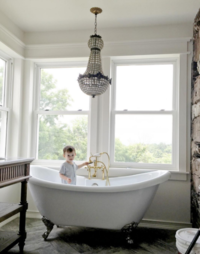 Photo of French chandelier and clawfoot bathtub in a bathroom remodel.