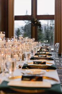 Table settings on a long table with many candles in the middle and large arch in the background