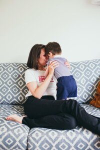 Kaya sitting on a patterned sofa, forehead to forehead with her young child Luca