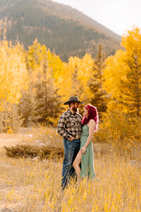 Couple standing among yellow trees during fall