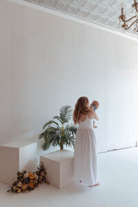 Mom embracing newborn in a family photo session in an all-white Missouri photography studio
