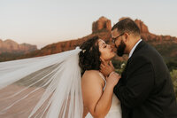 A newlywed couple about to kiss in front of red rocks 