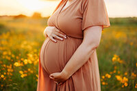 Pregnant mom hugs belly in a Memphis field during her maternity photo session by Jen Howell Photography.