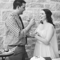 Black and white photo of Britni Dean and her husband eating cake at their wedding