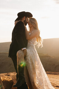 bride and groom standing on a rock cliff and embracing