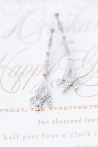earrings on top of white and copper wedding invitations