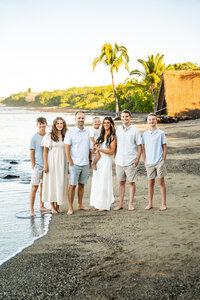 Multi generation family standing on beach smiling together during a Hawaiian family photoshoot