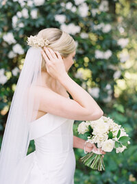 bride gently touching her veil and accessory
