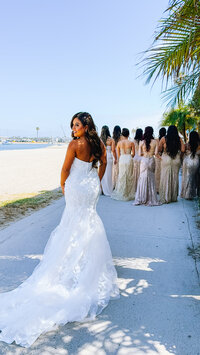 Bridal party and bride at beach in San Diego. Luxury wedding content creator capturing elegant bridesmaid dresses and natural white sand beach backdrop.