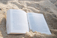 open book lying in sand
