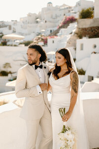 Bride and groom posing in Santorini village, highlighting destination elopement packages in Greece