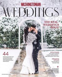 A couple dances in the snow under an archway, featured on the cover of Washingtonian Weddings magazines Winter 2023 issue. The bride wears a white dress with a fur shawl, and the groom is in a black suit. Snow-covered trees are in the background.