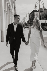 A photo of a couple walking down the street looking at one another 