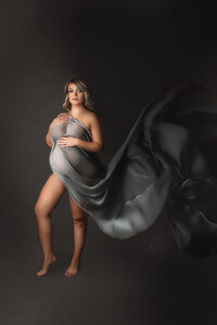expecting mother posed with flowing grey fabric at hamilton, ON maternity studio