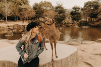 woman smiling while looking at deer