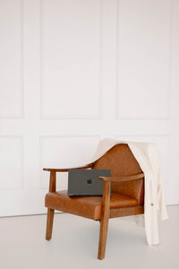 A laptop placed on a chair with an oversized blazer draped over the back, styled for Raechel Marie Photo’s brand imagery.