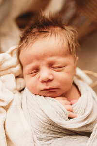 A little one with wild hair sleeps deeply during his newborn studio session with Nikii Pix Photography of Bismarck, ND