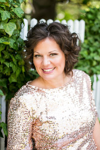 Brown haired woman smiles for portrait outdoors in sequin blouse