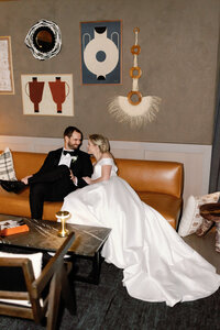 A stylish and modern wedding portrait at The Four Seasons in Houston, featuring a bride and groom lounging in a chic, art-filled setting with a luxurious and intimate vibe.