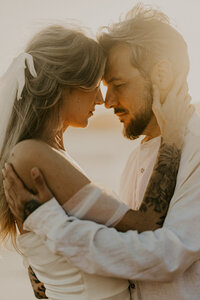 Couple se tenant front contre front au coucher du soleil lors d'un shooting photo en Vendée.