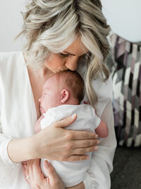 mom kissing newborn baby girl for in home photos