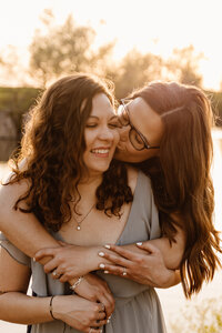 A person standing behind their partner kissing their cheek