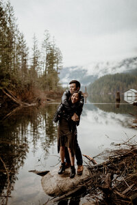 Cassandra and Wilson standing on a rock while hugging and smiling at their couple session at Buntzen Lake