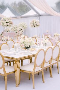 outdoor wedding plating decor with white and gold chairs and white florals