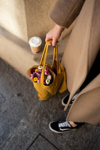A woman holding a bag of brightly colored flowers 