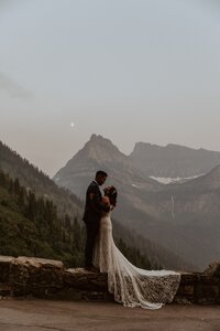 woman standing in front of mountains and holding her hair