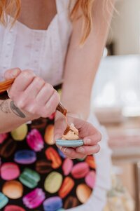 Detail image of baker piping icing into a macaroon during her Vancouver branding photography session