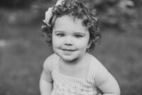 Black and white photo of a little girl smiling at the camera