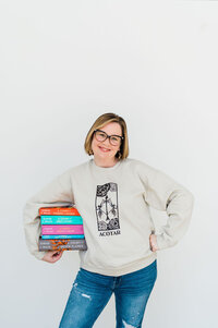 Copywriter Sara Gillis holding a stack of books