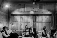 wedding guests sit in pairs at a large lounge in barn upstate