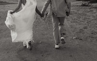 bride and groom running in the sand