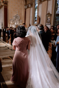 Catholic bride walks down the aisle with both of her parents.
