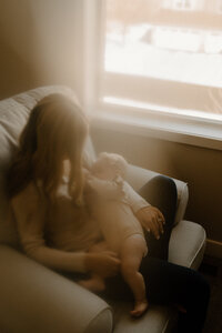 Mother photographed breastfeeding during New York City in-home maternity photoshoot