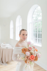 Bride holding bouquet of blush, white and orange florals