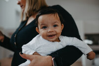 happy baby boy in mums arms in family home