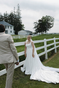 A bride and groom leaning against a barn fence, starting into each other's eyes during their wedding portraits. Captured by a Minnesota Wedding Photographer specializing in intimate, documentary style weddings.