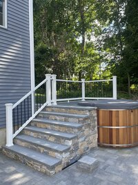 Stone stairs and white railings leading to a hot tub deck