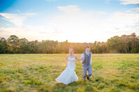Bride and groom running in a field