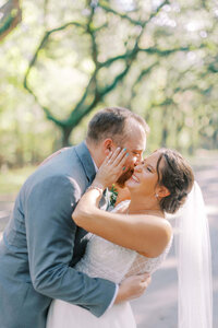 Bride and groom walking joyfully through a sunlit Savannah park, celebrating their elopement under moss-draped trees.