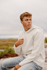A person sitting and looking off to the side in a field